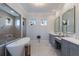 Bright bathroom featuring a soaking tub, glass shower, and dual vanity with marble countertops and natural light at 19424 Ganton Ave, Lakewood Ranch, FL 34202