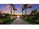 Inviting exterior view of a home with a meticulously landscaped front yard and stately palm trees against a sunset sky at 19424 Ganton Ave, Lakewood Ranch, FL 34202