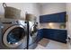 Well-equipped laundry room with front load machines, blue cabinets, and woven baskets for a modern touch at 19424 Ganton Ave, Lakewood Ranch, FL 34202