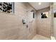 Modern shower with rainfall showerhead, handheld sprayer, and tiled walls with built-in shelving at 19424 Ganton Ave, Lakewood Ranch, FL 34202