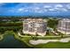 An aerial view features modern condos overlooking a lush golf course and beautiful waterfront scenery at 3010 Grand Bay Blvd # 482, Longboat Key, FL 34228