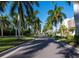 A tree-lined community drive features lush landscaping with manicured lawns and towering palm trees at 3010 Grand Bay Blvd # 482, Longboat Key, FL 34228