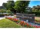 Bay Isles Beach Club entrance sign surrounded by vibrant red flowers and lush greenery on a sunny day at 3010 Grand Bay Blvd # 482, Longboat Key, FL 34228