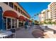 Outdoor dining area featuring tables with umbrellas, surrounded by lush landscaping and a view of the condominium at 3010 Grand Bay Blvd # 482, Longboat Key, FL 34228