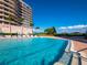 A clear blue swimming pool with chairs and palm trees, beside a well-maintained condominium community at 3010 Grand Bay Blvd # 482, Longboat Key, FL 34228
