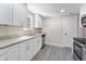 Well-lit kitchen features white cabinets, modern appliances, granite countertops, and gray wood-look flooring at 3457 50Th N Ave, St Petersburg, FL 33714