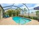 A screened in pool with a brick patio, featuring a stainless steel ladder and backyard foliage at 3839 Autumn Fern Ter, Sarasota, FL 34243