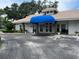 Exterior of clubhouse featuring a blue awning, tile roof, and well-maintained landscaping at 5708 Garden Lakes Fern, Bradenton, FL 34203