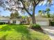 Charming single-story home with a lush green lawn, mature trees, and a two-car garage at 5708 Garden Lakes Fern, Bradenton, FL 34203