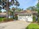 Two-car garage with decorative windows and mature landscaping surrounding the driveway at 5708 Garden Lakes Fern, Bradenton, FL 34203