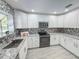 Modern kitchen featuring white cabinets, granite countertops, stainless steel appliances, and stylish backsplash at 5708 Garden Lakes Fern, Bradenton, FL 34203
