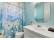 Bright bathroom features a vanity, sink, mirror, and shower with a decorative floral curtain at 5750 Saddle Oak Trl, Sarasota, FL 34241