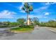 Community entrance with palm trees, landscaping, and a gatehouse on a sunny day at 5750 Saddle Oak Trl, Sarasota, FL 34241