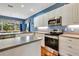 Modern kitchen with stainless steel appliances, white cabinets and blue accent wall at 5750 Saddle Oak Trl, Sarasota, FL 34241