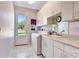 Well-lit laundry room with cabinets, a sink, and a door leading to the outside at 5750 Saddle Oak Trl, Sarasota, FL 34241
