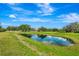 Picturesque pond reflects sky, surrounded by lush green grass, with home in background at 5750 Saddle Oak Trl, Sarasota, FL 34241