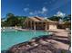 Community pool and lounging area with a large pool and tile roof clubhouse surrounded by mature landscaping at 8503 Gateway Ct, Englewood, FL 34224