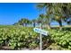 Lush tropical landscaping with a 'Beach' sign directing toward a beautiful sandy beach at 1125 W Peppertree Dr # 706, Sarasota, FL 34242