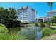 An elegant high-rise building set on a manicured lawn with a tranquil pond and fountain in view at 1125 W Peppertree Dr # 706, Sarasota, FL 34242