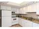 Well-lit kitchen with white cabinetry, granite countertops, and modern appliances at 1125 W Peppertree Dr # 706, Sarasota, FL 34242