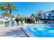 Community pool and clubhouse with lounge chairs, tropical landscaping, and clear blue skies at 1125 W Peppertree Dr # 706, Sarasota, FL 34242