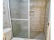 Clean shower featuring gray tiled walls, a grab bar, and a frosted glass door at 1125 W Peppertree Dr # 706, Sarasota, FL 34242