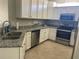 Bright kitchen features white cabinets, stainless steel appliances, granite counters, and tile flooring at 12229 Amica Loop, Venice, FL 34293