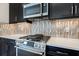 Close-up of a stainless steel range with a decorative backsplash and kitchen cabinets at 12518 Oak Hill Way, Parrish, FL 34219