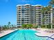 Resort-style pool with chairs and umbrellas with the high-rise condos in the background at 1281 Gulf Of Mexico Dr # 703, Longboat Key, FL 34228