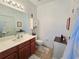 Bright bathroom featuring tile flooring, wood vanity and white sink, toilet and storage cabinet at 13602 Abercrombie Dr, Englewood, FL 34223