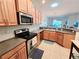 Well-lit kitchen featuring stainless steel appliances, light wood cabinets, and a corner sink at 13602 Abercrombie Dr, Englewood, FL 34223