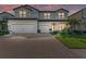 Two-story home featuring a three-car garage, brick driveway, and lush landscaping at 16438 Slate Pl, Lakewood Ranch, FL 34211