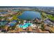 Aerial view showcasing a community clubhouse, swimming pool, and a scenic lake amid residential homes at 17026 Loudon Pl, Bradenton, FL 34202