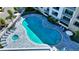 Aerial view of a luxurious pool and hot tub surrounded by lounge chairs, palm trees, and building at 1709 N Tamiami Trl # 408, Sarasota, FL 34234