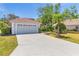 Home exterior with well-maintained lawn, concrete driveway, and a red tile roof under a clear blue sky, highlighting the landscaping at 2100 Waweep Ct, Sarasota, FL 34235