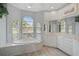 Bright and airy bathroom with soaking tub, neutral colors and light wood-look flooring at 2136 Muskogee Trl, Nokomis, FL 34275