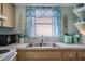 Kitchen with wood cabinets, stainless steel sink, window with blue curtains and decor at 2907 51St W Ave, Bradenton, FL 34205