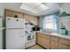 Bright kitchen featuring white appliances, wood cabinets, and a window with blue curtains at 2907 51St W Ave, Bradenton, FL 34205