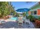 Outdoor patio with a pool, lush landscaping and seating area with blue umbrella at 3007 Avenue E # A, Holmes Beach, FL 34217
