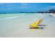 Relaxing beach scene with two yellow beach chairs on the soft sand, complemented by gentle waves at 3977 Roberts Point Rd, Sarasota, FL 34242