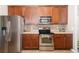 Modern kitchen with stainless steel appliances, wooden cabinets, and views of the adjacent dining area at 5814 117Th E Ter, Parrish, FL 34219