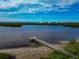 Scenic view of private pier extending into the calm waterfront with lush green surroundings and a bright cloudy sky at 617 Estuary Dr # 617, Bradenton, FL 34209