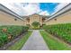 Landscaped walkway leads to the front entrance of the condo building on a sunny day at 6326 Grand Oak Cir # 203, Bradenton, FL 34203