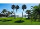 Expansive green backyard of waterfront home with swaying palm trees and views of open bay at 684 Freeling Dr, Sarasota, FL 34242