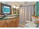 Cozy bathroom with wooden cabinets, patterned shower curtain, and a vintage-style mirror at 805 Mcarthur Ave, Sarasota, FL 34243