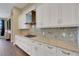 Bright kitchen featuring white cabinetry, granite counters, gas cooktop and stainless steel range hood at 8901 Artisan Way, Sarasota, FL 34240
