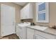 Well-lit laundry room features modern appliances, countertop with sink, and ample storage at 8901 Artisan Way, Sarasota, FL 34240