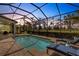Relaxing screened-in pool area with lounge chairs and scenic backyard views at dusk at 8901 Artisan Way, Sarasota, FL 34240