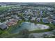 Aerial view of a residential area with houses, a pond, green spaces, and palm trees on a sunny day at 1113 Cane Mill Ln, Bradenton, FL 34212