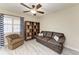 Comfortable living room features a brown leather sofa and a wooden bookshelf, illuminated by a ceiling fan at 1153 Edgewater Cir, Bradenton, FL 34209